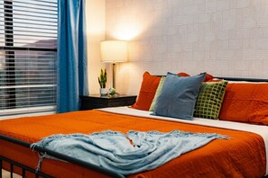 A hotel room with a bed, a nightstand, a lamp, and a window with blinds. - Resort-Style Retreat: Pool • Spa • Game Room (Scottsdale)