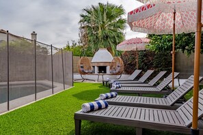 A backyard with a pool, lounge chairs, a hanging chair, and a barbecue area. - Resort-Style Retreat: Pool • Spa • Game Room (Scottsdale)