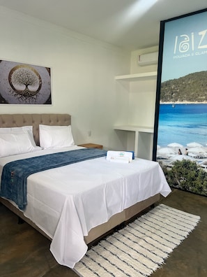 Een slaapkamer met een bed, een groot raam met uitzicht op zee en een schilderij aan de muur.