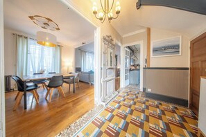 Ein geräumiges Zimmer mit Holzesstisch, Stühlen, einem gemusterten Teppich und einer Pendelleuchte.