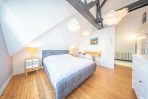Ein Schlafzimmer mit einem Bett, Nachttischen, einer Kommode und einem Bild an der Wand.