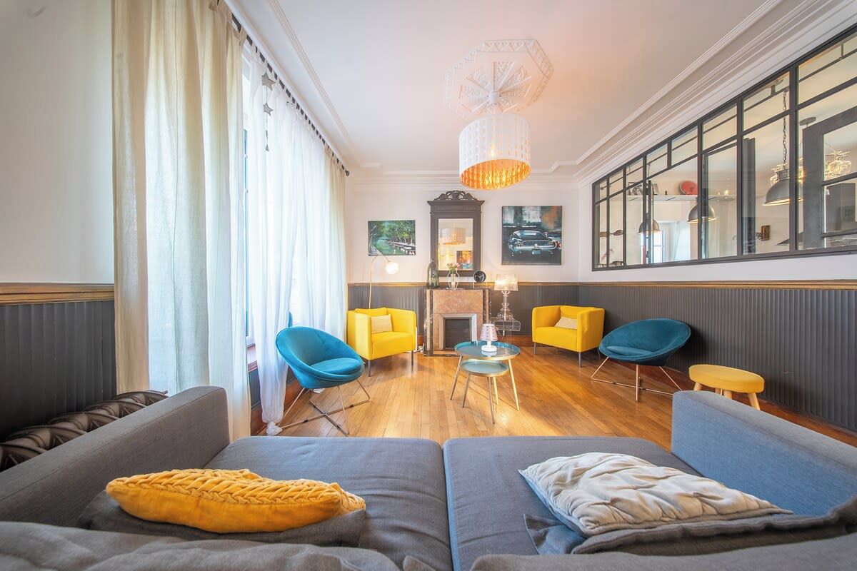 A modern living room with a fireplace, two sofas, a coffee table, and a large window with curtains.