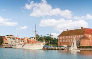 A harbor with a large sailing ship docked, a smaller sailboat, and a historic building with a red roof. - Nice home in Sydals with WiFi (Sydals)
