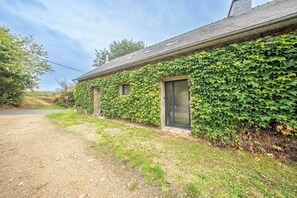 A house with ivy-covered walls, a gravel driveway, and a clear sky. - Appartement Cosy au coeur de la nature (Riec-sur-Bélon)
