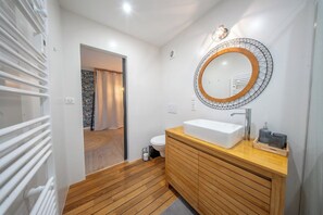 A modern bathroom with a wooden vanity, a large mirror, and a white sink. - Appartement Cosy au coeur de la nature (Riec-sur-Bélon)
