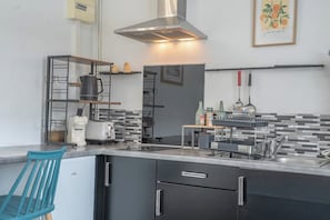 Eine kompakte Küche mit Einbauherd, einer Kaffeemaschine und einem Spülbecken.