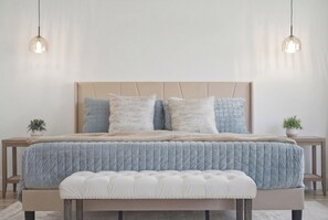 A bed with a tufted headboard, a matching bench, and two bedside tables with lamps. - Golden Hour 1 story 4 BR 3-car garage GATED (Las Vegas)