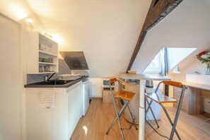 A compact kitchen with white cabinetry, a small countertop, and a foldable stool. - Studio au Cœur du centre historique (Quimper)