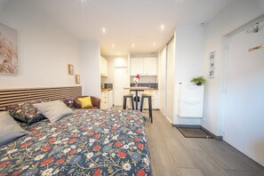 A bedroom with a bed, a desk, and a kitchenette. - Le pied-à-terre idéal au centre (Quimper)