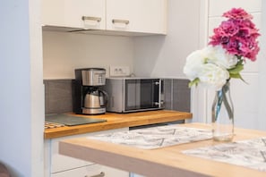 A kitchen with a microwave, coffee maker, and a vase with flowers on the counter. - Le pied-à-terre idéal au centre (Quimper)