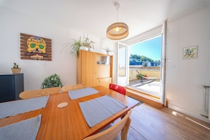 Ein Essbereich mit einem Holztisch, roten Stühlen und Blick durch eine Glastür nach draußen.