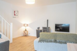 Ein modernes Wohnzimmer mit Flachbildfernseher, Kamin, Lampe und einer Couch.
