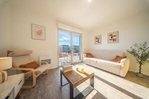 A modern living room with a sofa, armchair, and a coffee table. - T2 neuf & lumineux Calme et plages à 5 min (Guidel)