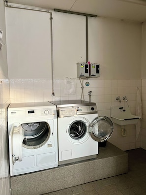 A laundry area with two front-loading washing machines, a sink, and a towel rack. - Kaiserplatz Suite in a Prime Location (Bad Reichenhall)