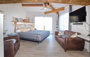 A bedroom with a bed, a sofa, a television, and a ceiling fan. - Amazing home in Folelli with private swimming pool, can be inside or outside (Folelli)