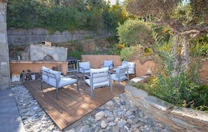 An outdoor patio with stone walls, a grill, and white cushioned seating. - Amazing home in Folelli with private swimming pool, can be inside or outside (Folelli)