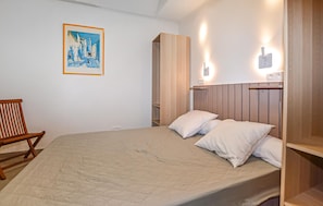 A bedroom with a bed, a wooden chair, a wardrobe, and a painting on the wall. - Amazing home in Folelli with private swimming pool, can be inside or outside (Folelli)