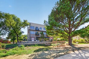 A multi-story building with a flat roof, large windows, and a paved entrance area with outdoor seating. - Tunnel Vision Loft · 2BR by Trails & Bike Shop (Bella Vista)