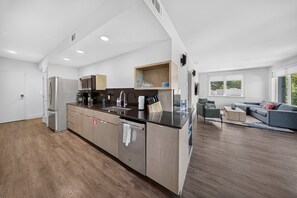 Una cocina moderna con horno empotrado, cafetera y pileta.