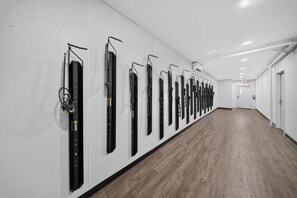 Ein langer Korridor mit an der Wand montierten Skiern, einem Holzboden und weißen Wänden.