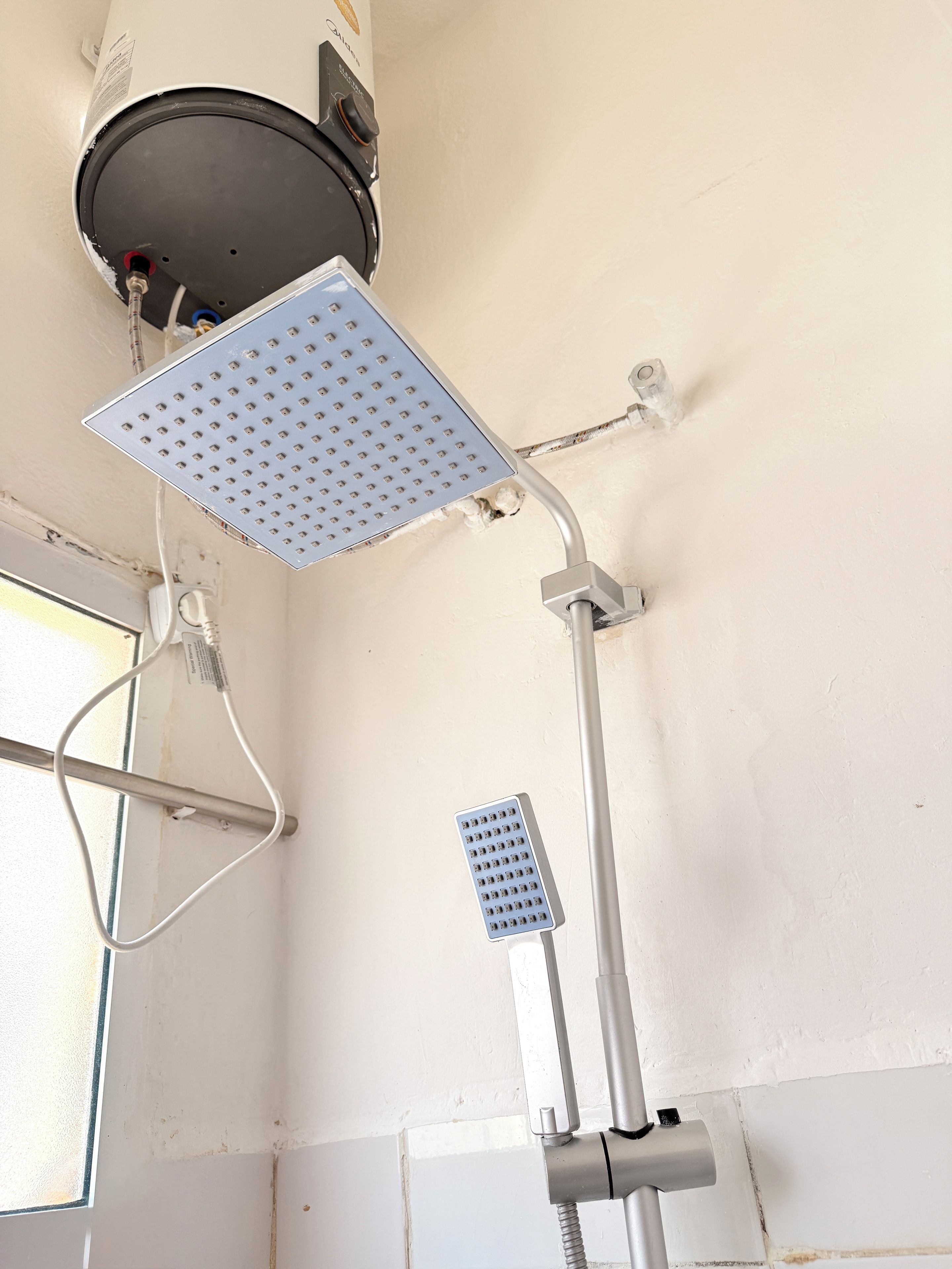 A shower area with a handheld showerhead and a fixed showerhead mounted on the wall.
