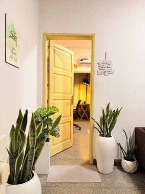 A hotel room with a door leading to a dining area, a potted plant, and a wall-mounted sign. - Cozy & Secure 1BR Apartment City Center (Luanda)