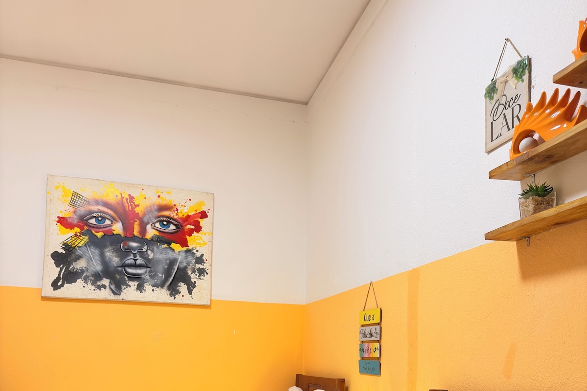 Una habitación de hotel con dos camas, un cuadro en la pared y un estante con objetos decorativos.