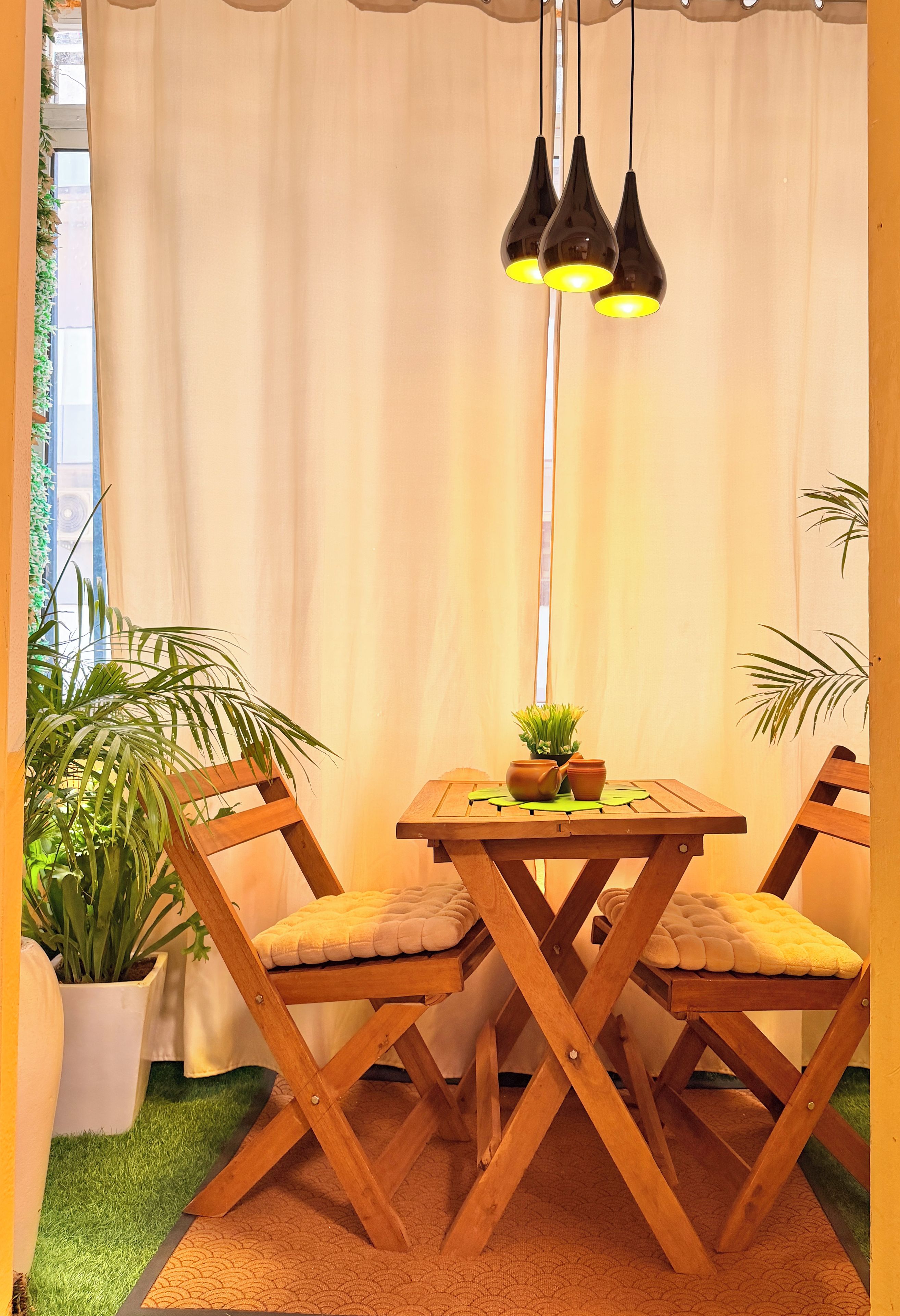 A dining area with a wooden table and chairs, a hanging light fixture, and potted plants.