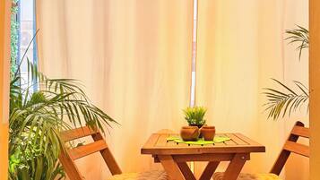 A dining area with a wooden table and chairs, a hanging light fixture, and potted plants.