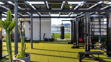 An outdoor gym area with exercise equipment, a punching bag, and potted plants.