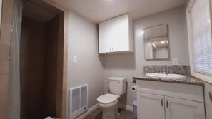 Un bany amb vàter, un lavabo, un mirall i armaris.