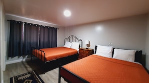 Une chambre d’hôtel avec deux lits, une table de chevet, une lampe et une fenêtre avec des rideaux.