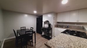 Une cuisine compacte comprenant une table à manger, des chaises, un réfrigérateur noir, une machine à café et une cuisinière.