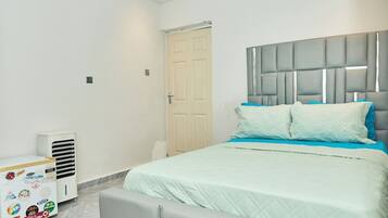 Un dormitorio con una cama, cabecera, una puerta y un equipo de aire acondicionado blanco.