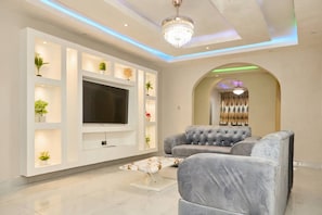 Una sala de estar moderna con un televisor de pantalla plana, sofás tapizados en gris y un arco decorativo.