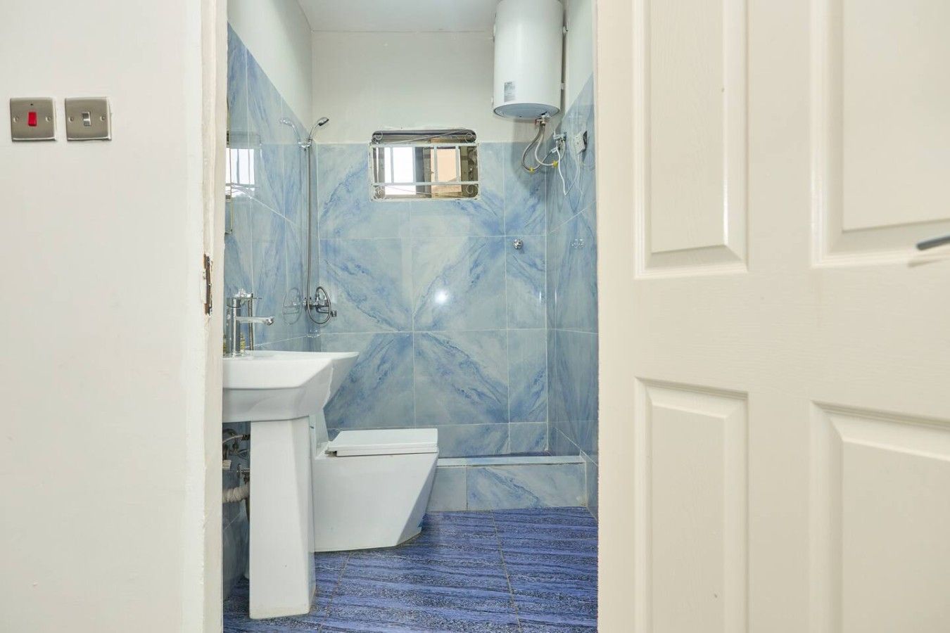 Un baño con lavamanos blanco, inodoro y zona de ducha.