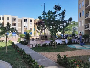 A residential building with a courtyard, outdoor seating area, and a basketball court. - Lindo Apartamento con Piscina Girardot · Hasta 10 personas (Girardot)