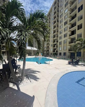 A pool area with a building in the background. - Lindo Apartamento con Piscina Girardot · Hasta 10 personas (Girardot)