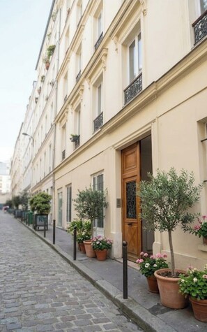 A row of buildings with a cobblestone street, wooden doors, and potted plants. - Studio Apartment Between Bastille and Voltaire - Quiet Courtyard - Paris 11th Arrondissement (Paris)