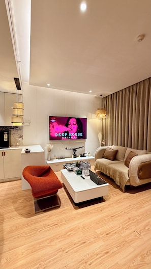 Ein modernes Wohnzimmer mit Flachbildfernseher, einer Couch, einem roten Sessel und einem Couchtisch.