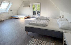 Ein Schlafzimmer mit einem großen Bett, einem kleinen Nachttisch, einem Fenster und einer Klimaanlage.