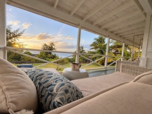 A room with a view of the ocean, a wicker sofa, and a decorative vase. - Poipu Ocean View Beach House  - Sleeps 6 (Koloa)