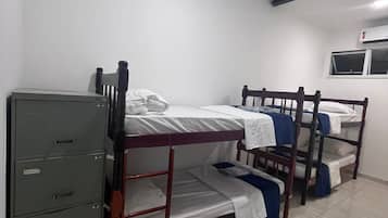 A dormitory room with bunk beds, a filing cabinet, and a window.