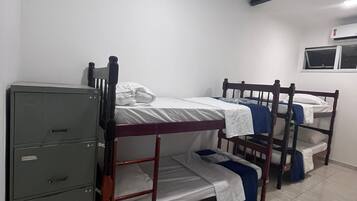 Une chambre de dortoir avec des lits superposés, un classeur et une fenêtre.