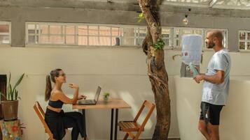 Une pièce avec une table en bois, un ordinateur portable, une plante en pot et un grand tronc d’arbre.
