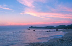 A beach with calm waters, distant mountains, and a clear sky. - 2 bedroom cozy apartment in Costa Rei (Costa Rei)