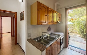 A kitchen with wooden cabinets, a stainless steel sink, and a countertop. - 2 bedroom cozy apartment in Costa Rei (Costa Rei)