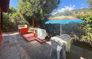 Une terrasse extérieure avec une table, des chaises et un parasol coloré.