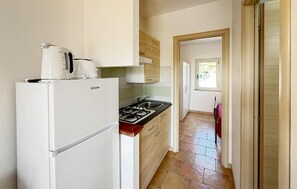A compact kitchen with a white refrigerator, a stove, and a sink. - 1 bedroom amazing apartment in Costa Rei (Costa Rei)