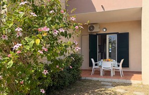Eine Terrasse mit einem für das Frühstück gedeckten Tisch, einem Fenster mit Rollläden und einer wandmontierten Klimaanlage.